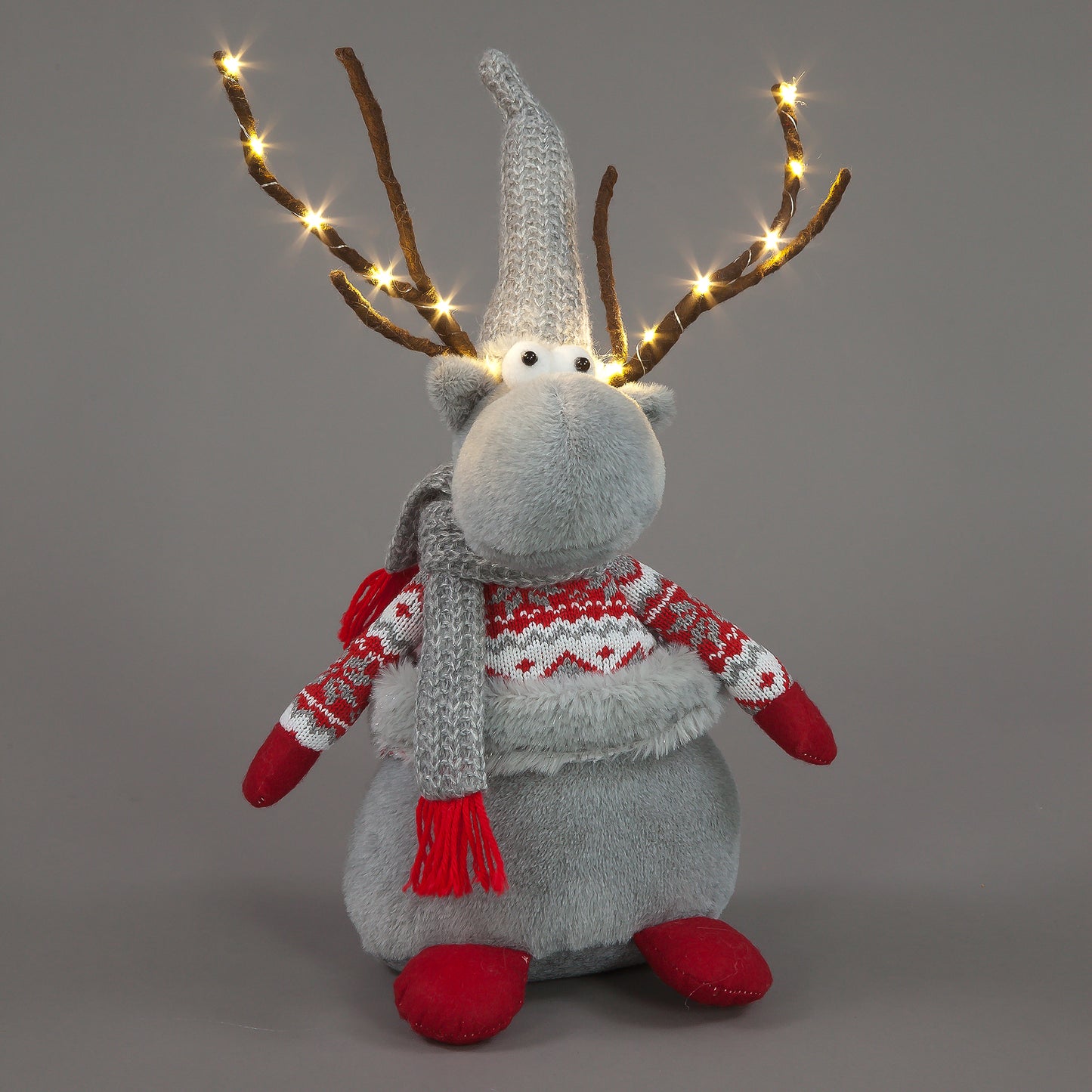 Gray reindeer plush toy with lights, sweater, and scarf on a gray background