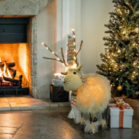 Decorative reindeer in a cozy living room with a fireplace and Christmas tree.
