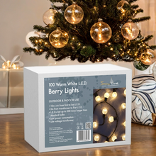 Box of Snowtime berry lights in front of a decorated Christmas tree