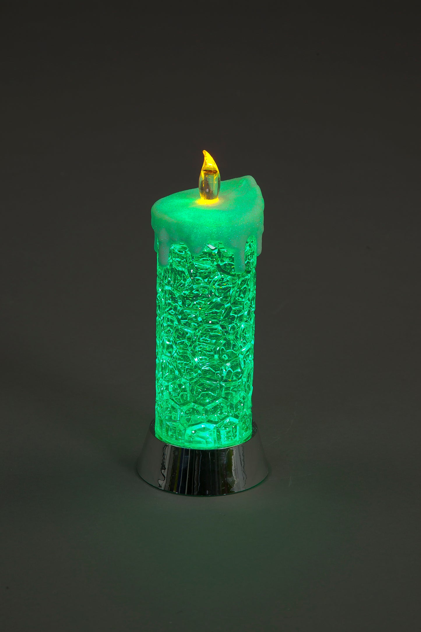 Green textured candle with a flame on a dark background