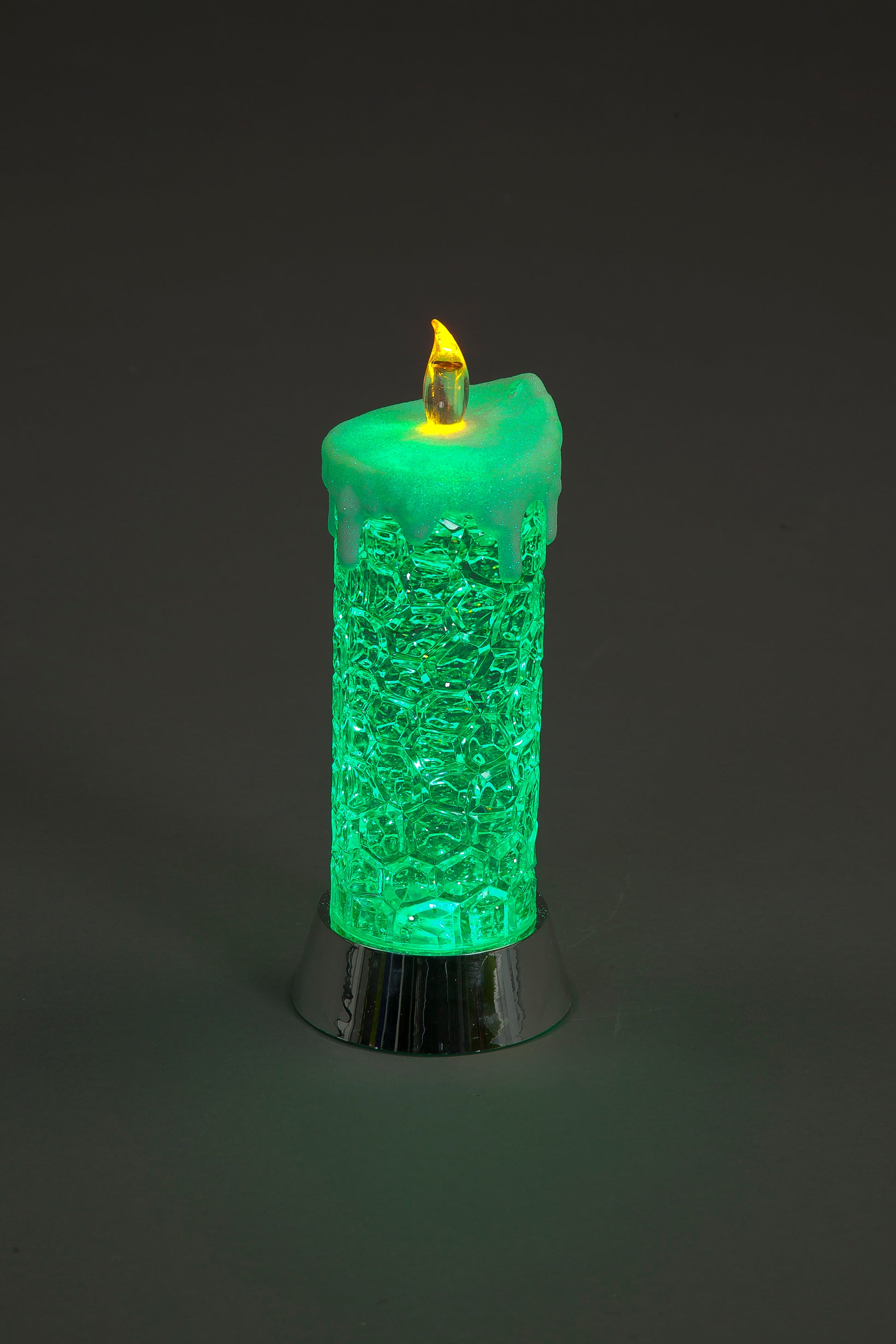 Green textured candle with a flame on a dark background
