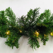 Green artificial Christmas garland with lights on a white background